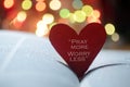 Inspirational quote on a red heart - Pray more, worry less. On open bible book page and colorful bokeh lights background. Royalty Free Stock Photo
