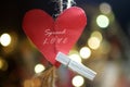 Inspirational quote - Spread love. With red heart shape, a white wooden paper clip and beautiful Christmas bokeh lights background