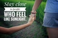 Inspirational quote - Stay close to people who feel like sunlight. With couple holding hands in the field on green paddy plants.