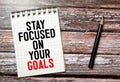 Inspirational quote - Stay focused on your goals. With text message on white paper book, pen Royalty Free Stock Photo