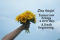 Inspirational quote - Stay hopeful. Tomorrow brings a new day. A fresh beginning. With hand holding beautiful bouquet of sunflower