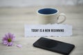 Inspirational quote - Today is a new beginning. With morning a cup of coffee, black smartphone and purple daisy flower . Royalty Free Stock Photo