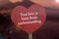 Inspirational quote - True love is born from understanding. Text message on light red sign board with heart shaped. Love care. Royalty Free Stock Photo