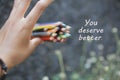 Inspirational quote - You deserve better. With an illustration background of young woman hand release a bunch of colored pencils.