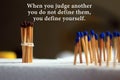Inspirational quote - When you judge another, you do not define them, you define yourself. With background of colorful matches.