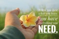 Inspirational quote - When you love what you have, you have everything you need. With hand holding Bali frangipani flower.