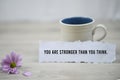 Inspirational quote - You are stronger than you think. With a cup of morning coffee and beautiful purple daisy flower.