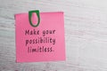 Inspirational quotes on red sticker with paper clip on top of wooden desk.