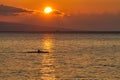 Inspirational kayaker rowing across the sunset lit ocean on Maui.