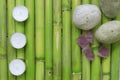 Inspirational scene with three candles aligned, stones and gemstones on a natural green bamboo background.