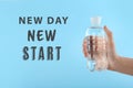 Inspirational text New Day New Start and woman holding bottle of water on blue background Royalty Free Stock Photo