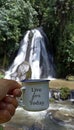 Inspirational text quote on a mug in hand - Life for today. With person holding traditional cup of tea or coffee against waterfall Royalty Free Stock Photo