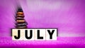 inspirational time concept - word july on wooden blocks with stack of stones in purple vintage background