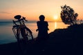 Inspirational view caucasian male cyclist sit by touring bicycle looking to scenic relaxing golden sunset background by sevan lake