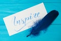 Inspire. Beautiful blue letters on canvas with blue feather. Calligraphy script. Art of writing letters. Background