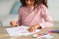 Inspired african american teen girl with brush and palette painting, enjoying her new hobby, sitting at desk at home Royalty Free Stock Photo