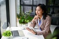 Inspired and attractive millennial Asian businesswoman looking out the window, daydreaming Royalty Free Stock Photo