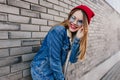 Inspired european girl in trendy jeans posing near brick wall. Outdoor photo of glad blonde lady to