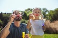 Inspired father blowing bubbles with his daughter