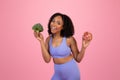 Inspired happy millennial african american woman in sportswear show broccoli and donut
