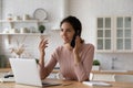 Inspired hispanic woman remote worker sitting by laptop making call