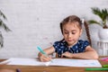 Inspired little girl at the table draw with crayons or do home work Royalty Free Stock Photo
