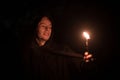 Inspired male portrait with candle in hand night time story concept picture in darkness environment, soft focus on face and noise