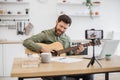 Inspired man playing guitar while recording video on mobile