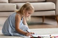 Inspired preschool girl sitting on warm floor drawing imaginary world