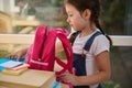 Inspired schoolgirl folding school supplies in a pink knapsack, getting ready for the first grade of elementary school