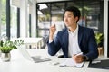 Inspired Asian businessman enjoying his morning coffee at his desk in the office Royalty Free Stock Photo