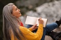 Inspired woman with an albom in hands on the river bank