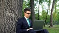 Inspired young businessman working on grass in park, escaping office routine Royalty Free Stock Photo