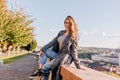 Inspired young female model in gray coat posing in park after riding on bicycle and smiling. Fashionable woman in blue Royalty Free Stock Photo