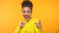 Inspired young woman pointing hands in camera on yellow background, motivation