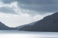 Inspiring majestic sunbeams streaming through dramatic clouds onto calm waters of Loch Lomond landscape during Winter sunset Royalty Free Stock Photo