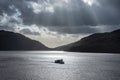 Inspiring majestic sunbeams streaming through dramatic clouds onto calm waters of Loch Lomond landscape during Winter sunset Royalty Free Stock Photo