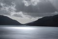 Inspiring majestic sunbeams streaming through dramatic clouds onto calm waters of Loch Lomond landscape during Winter sunset Royalty Free Stock Photo