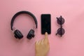 instagram blogging concept. hand showing stylish black phone, sunglasses and headphones on pink background, flat lay. modern hips Royalty Free Stock Photo