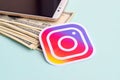 Instagram paper logo lies with envelope full of dollar bills and smartphone