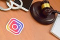 Instagram paper logo lies with wooden judge gavel, smartphone and handcuffs. Entertainment lawsuit concept