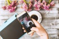 Instagram photographer blogging workshop concept, hand holding phone and taking photo of stylish flowers, cup of coffee