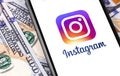 Instagram symbol on the display smartphone with dollars money