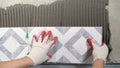 Instaling ceramic tiles. Male hands glue ceramic tiles on the wall in the bathroom. Royalty Free Stock Photo