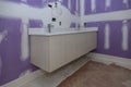 Installation of cabinet with drawers for wash basins, stainless steel faucet for sink at toilet, a white porcelain sink Royalty Free Stock Photo