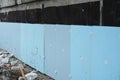 Installation of extruded polystyrene slabs or XPS rigid foam thermal insulation sprayed on tar to insulate the foundation, Royalty Free Stock Photo