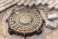 Installation of a heavy cast iron sewer manhole on a well before paving slabs. Sewerage system in construction. Close-up
