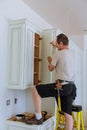 Installation of kitchen. Worker installs doors to kitchen cabinet.