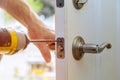 Installation locked interior door knobs, close-up woodworker hands install lock.