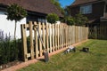 The installation of a wooden, natural wood colour, picket fence in a residential garden